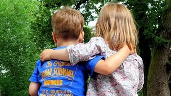 Two children sitting next to each other hugging