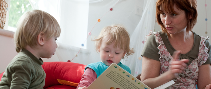 Tagesmutter liest ein Buch mit Kleinkindern