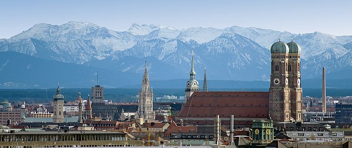 Frauentürme und Altstadt Münchens vor Bergpanorama.